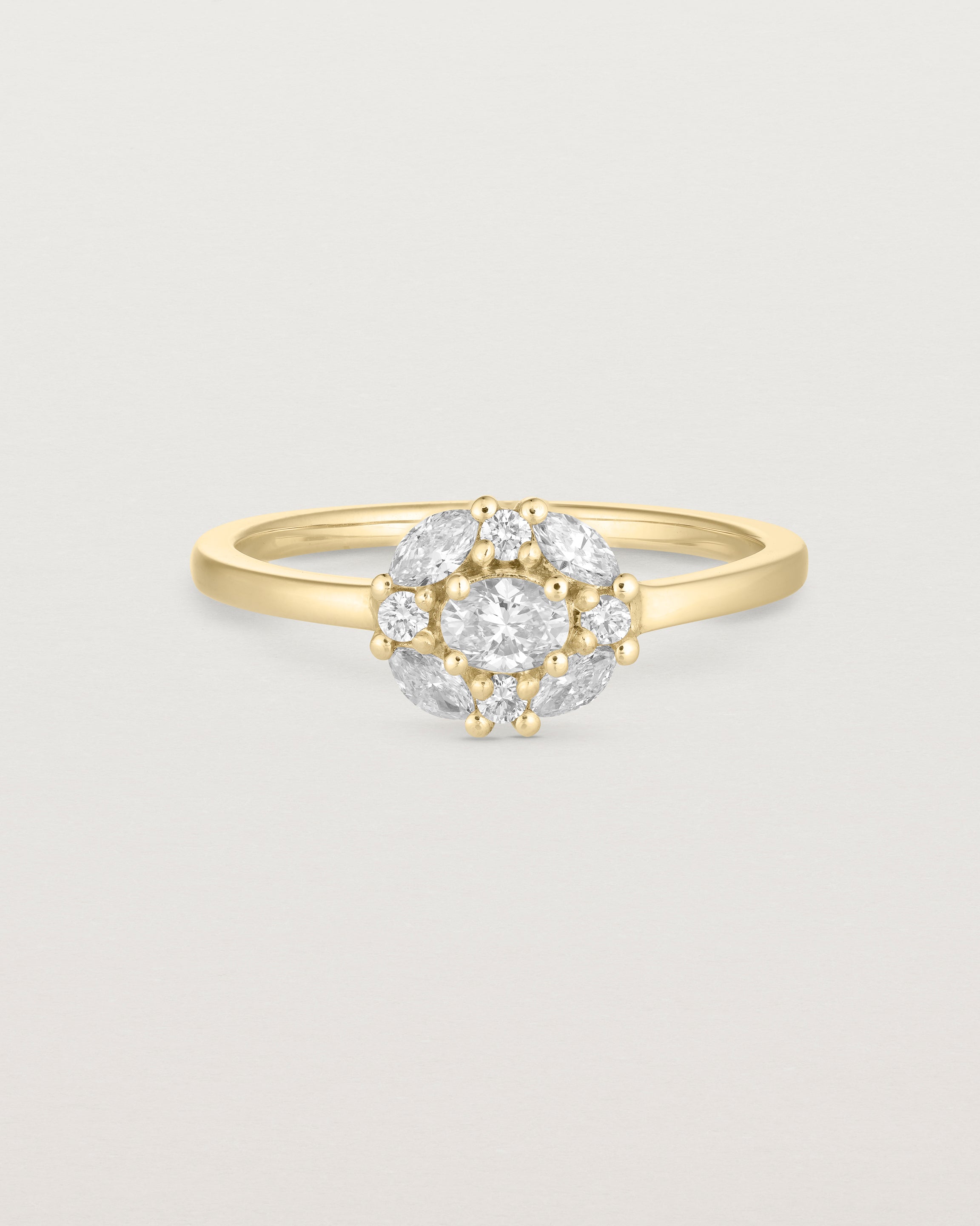 deep etched image of a yellow gold engagement ring with an oval white diamond and a halo of eight diamonds. 