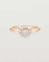 Front on deep etched image of a rose gold engagement ring with an oval white diamond and a halo of eight diamonds.