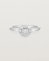 Front on deep etched image of a white gold engagement ring with an oval white diamond and a halo of eight diamonds.