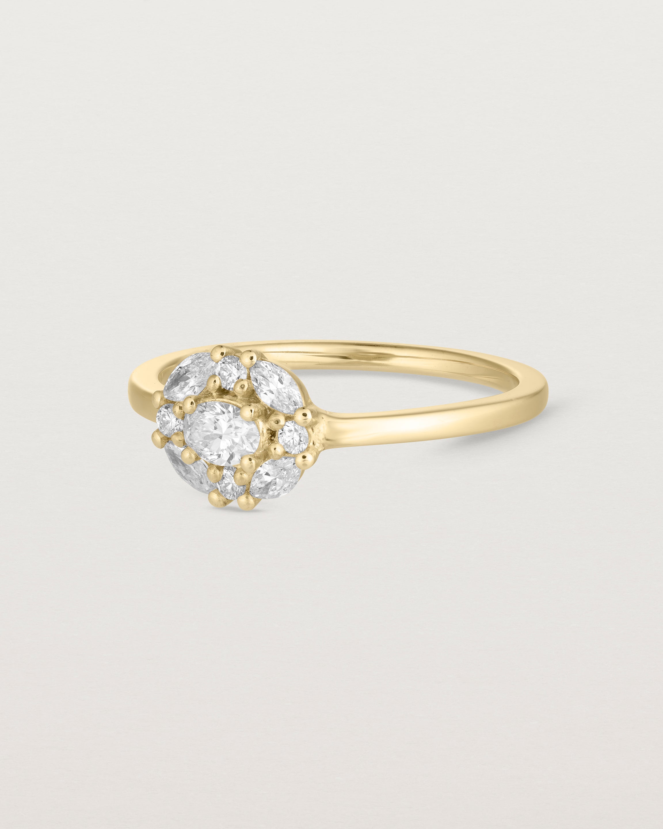 side angle of deep etched image of a yellow gold engagement ring with an oval white diamond and a halo of eight diamonds. 