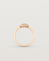 Standing deep etched image of a rose gold engagement ring with an oval white diamond and a halo of eight diamonds.