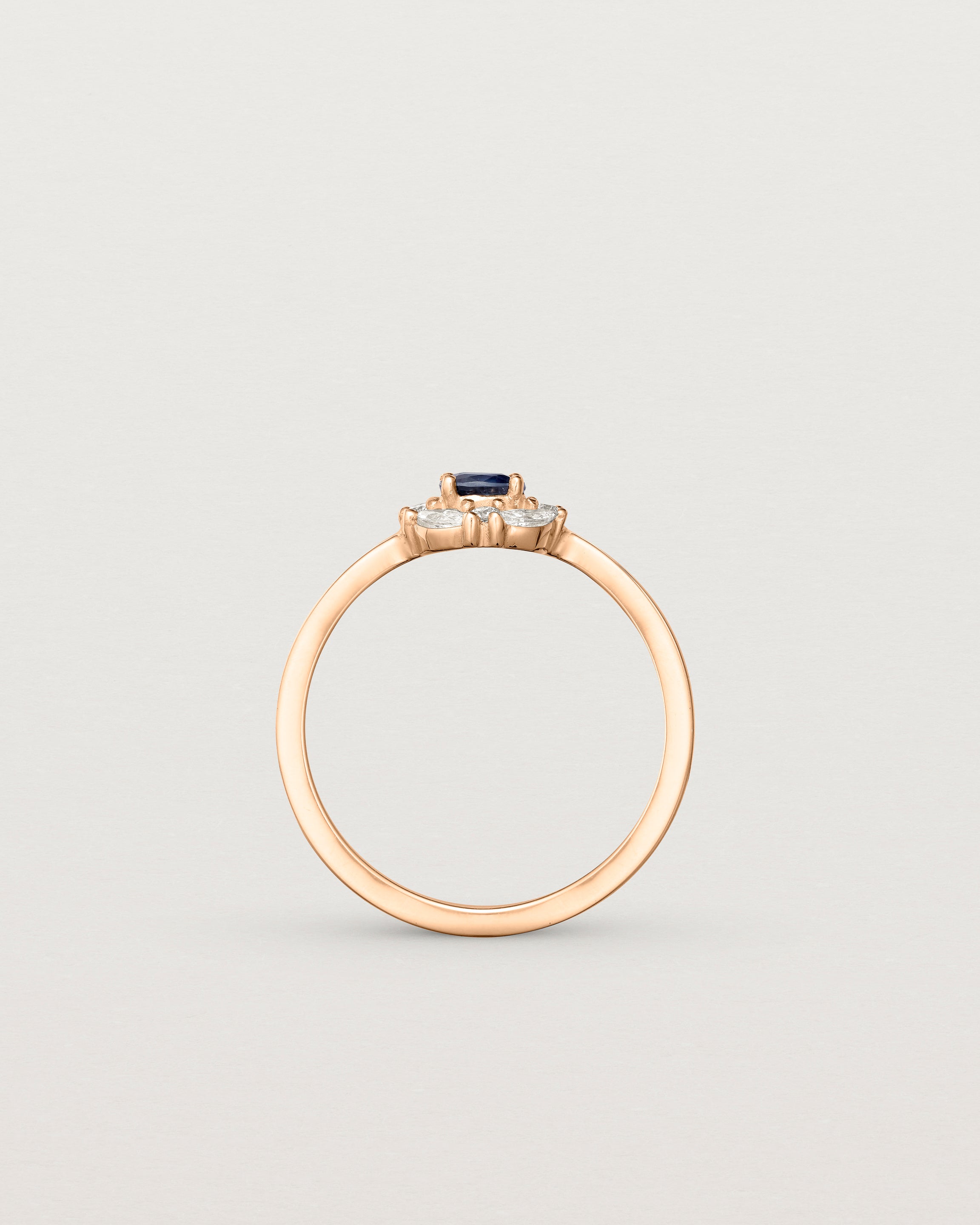 Standing deep etched image of a rose gold engagement ring with an oval white diamond and a halo of eight diamonds.