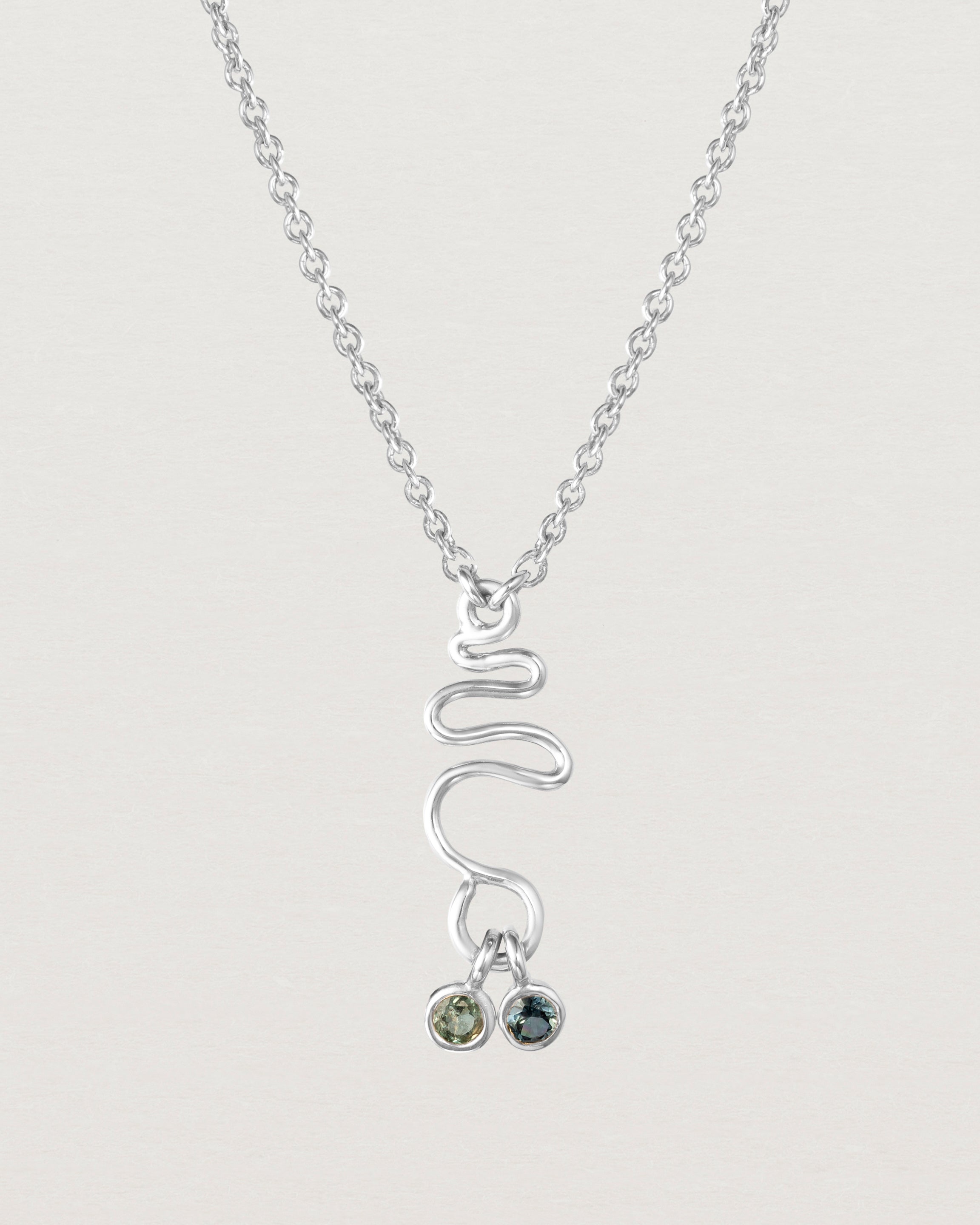 Front on deep etched image of a white gold necklace with birthstone charms.