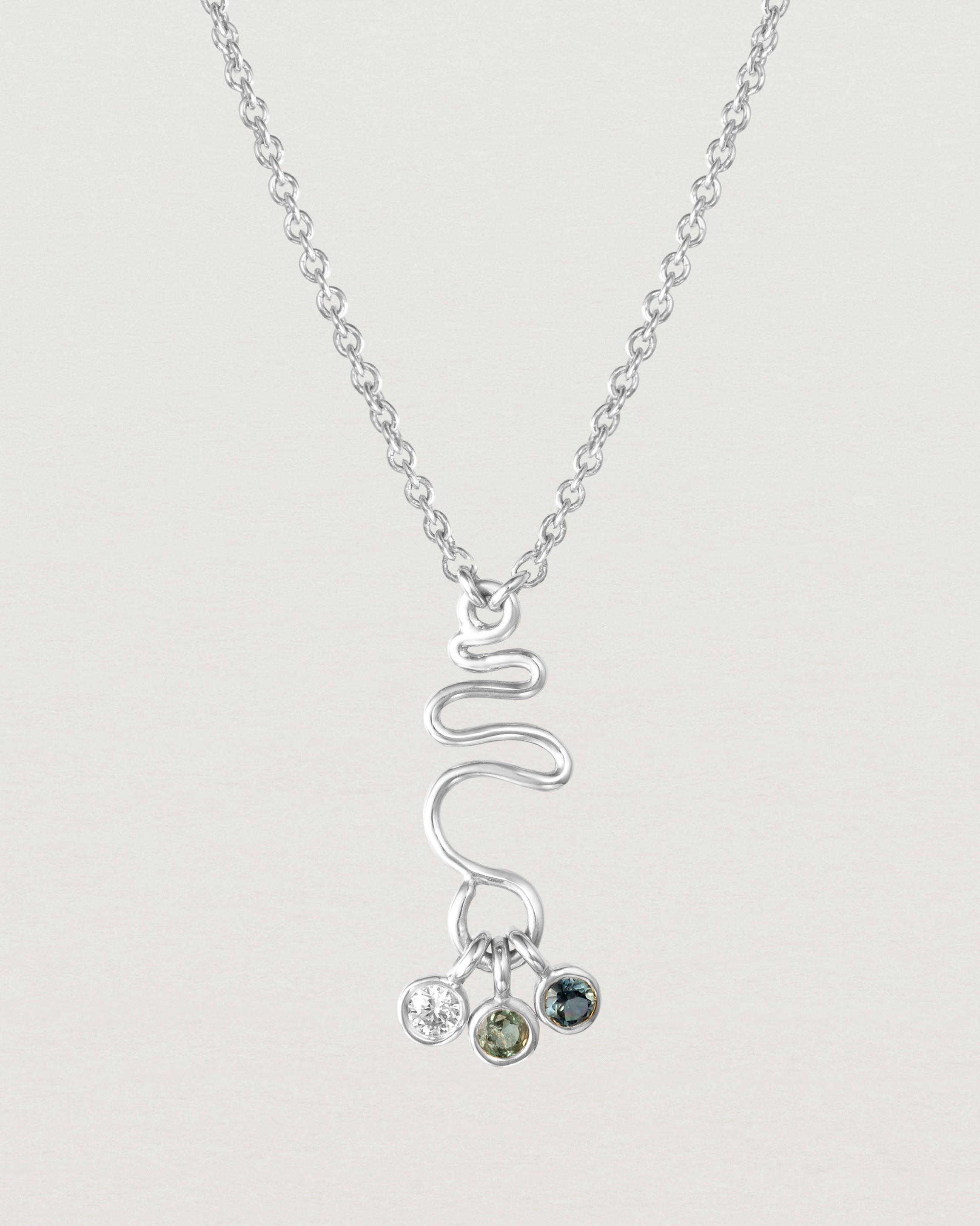 Front on deep etched image of a white gold necklace with birthstone charms.