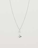 Front on deep etched image of a white gold necklace with birthstone charms.
