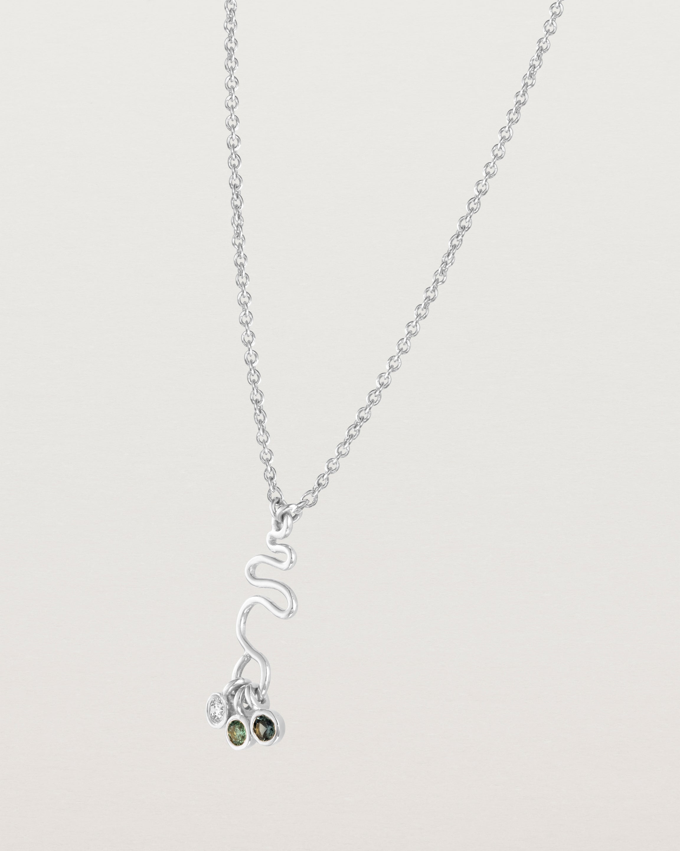 Side facing deep etched image of a white gold necklace with birthstone charms.
