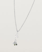 Side facing deep etched image of a white gold necklace with birthstone charms.
