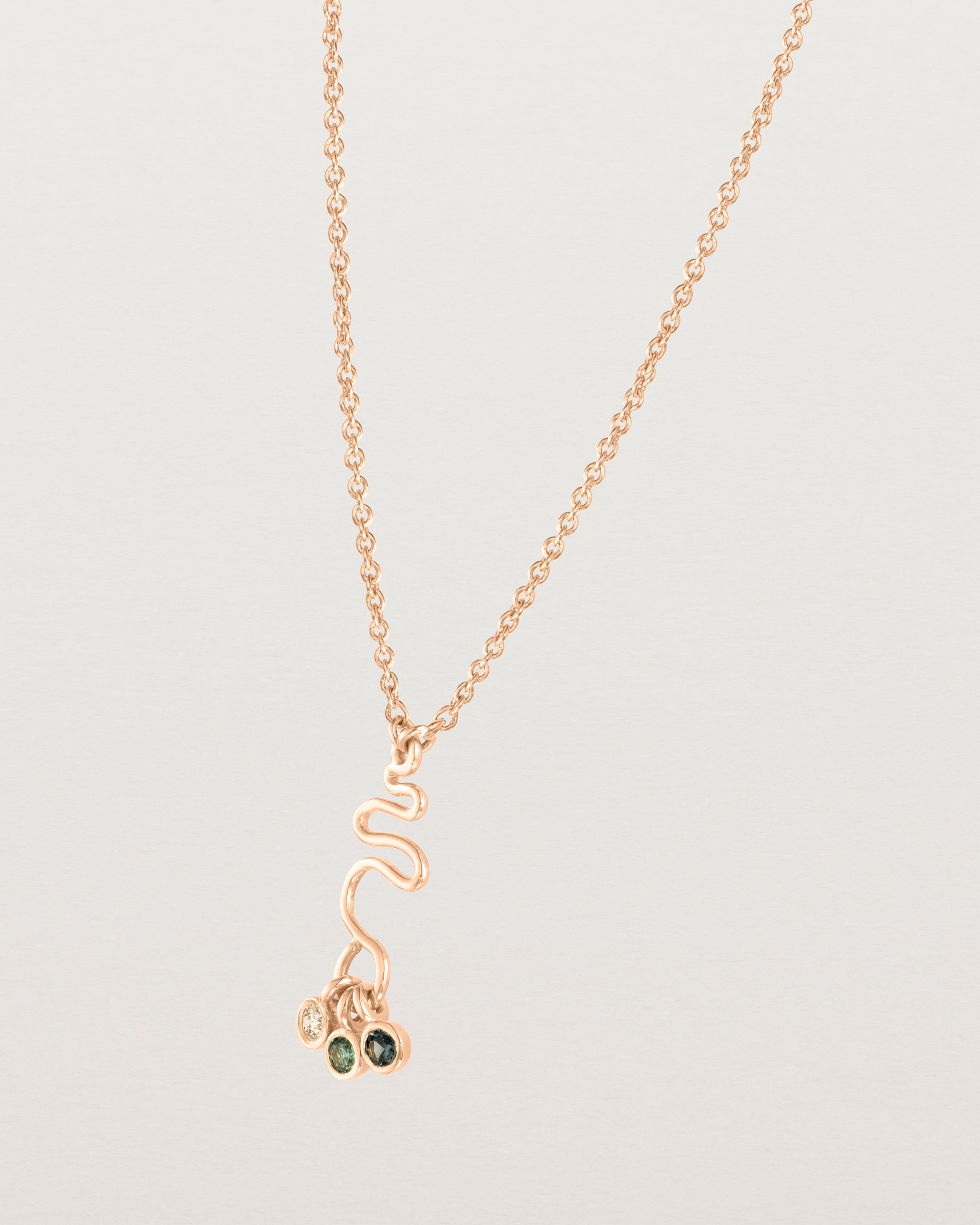 Side facing deep etched image of a rose gold necklace with birthstone charms.
