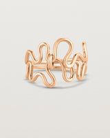 Side facing deep etched image of a rose gold ring set with charms.
