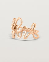 Side facing deep etched image of a rose gold ring set with charms.
