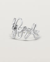 Side facing deep etched image of a white gold ring set with charms.
