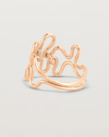 Back facing deep etched image of a rose gold ring set with charms.
