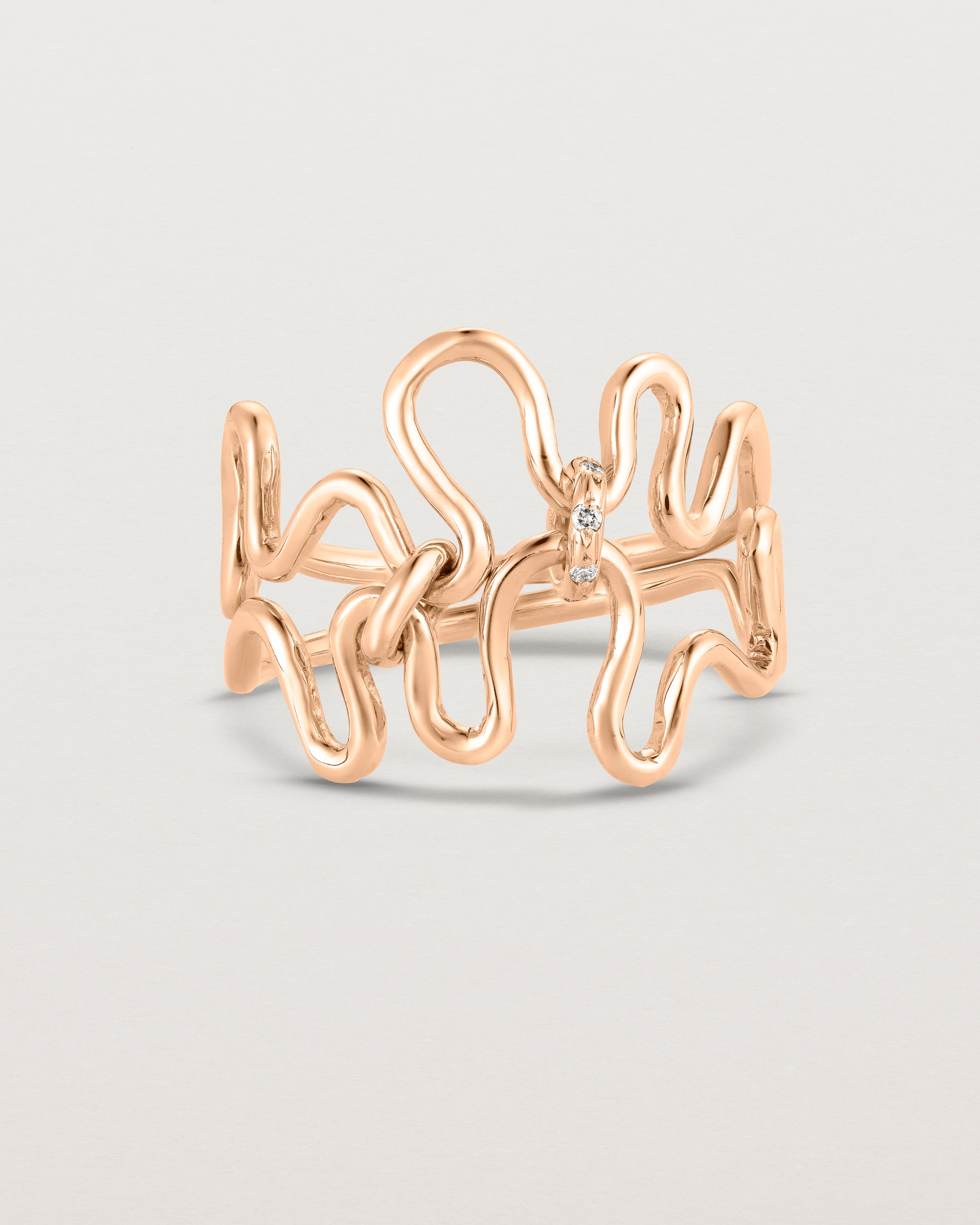 Front facing deep etched image of a rose gold ring set with charms.
