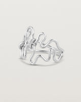 Side facing deep etched image of a white gold ring set with charms.
