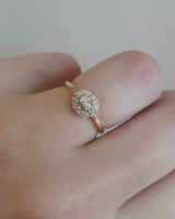 Front on deep etched video of a yellow gold engagement ring with an oval white diamond and a halo of eight diamonds.